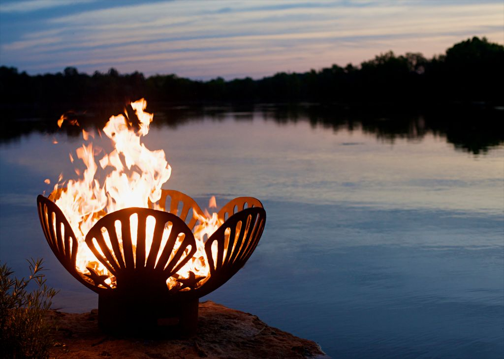 Barefoot Beach Fire Pit glowing flames reflected on calm water at twilight
