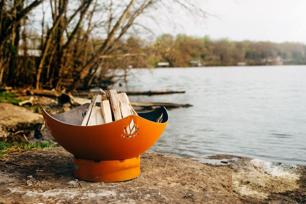 Firepit Art bowl with large fire and woman in lotus pose by the water